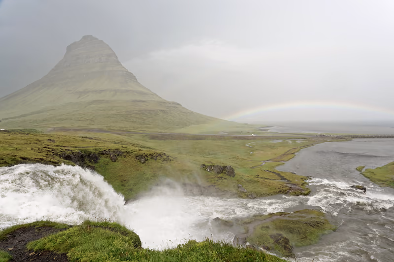 Kirkjufell mountain above the Kirkjufellsfoss waterfall, a faint rainbow in the rain