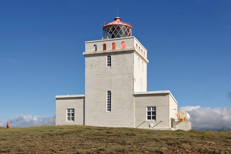 The white lighthouse on Dyrhólaey under a blue sky