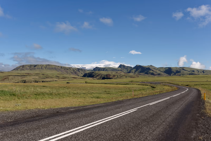 Road 215 curving through green fields toward the mountains